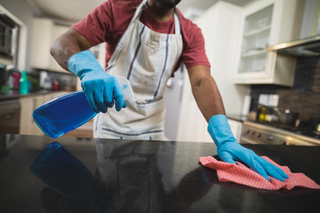 mid section man cleaning black marble counter in kitchen at home