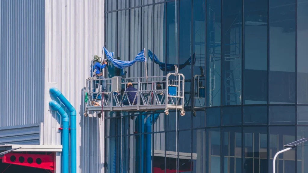 builder on suspended platform installing glass